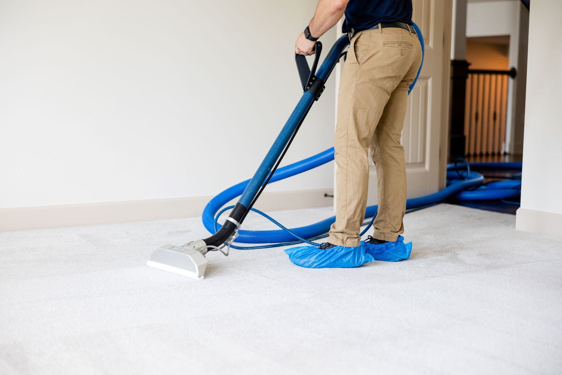 A man is cleaning a carpet with a vacuum cleaner.